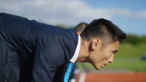 Businessman wearing suit in starting position for a foot race with other businessmen